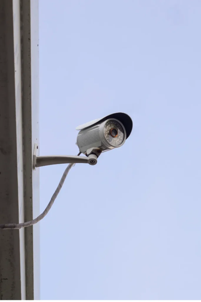Outdoor security camera mounted on a building wall against a clear sky
