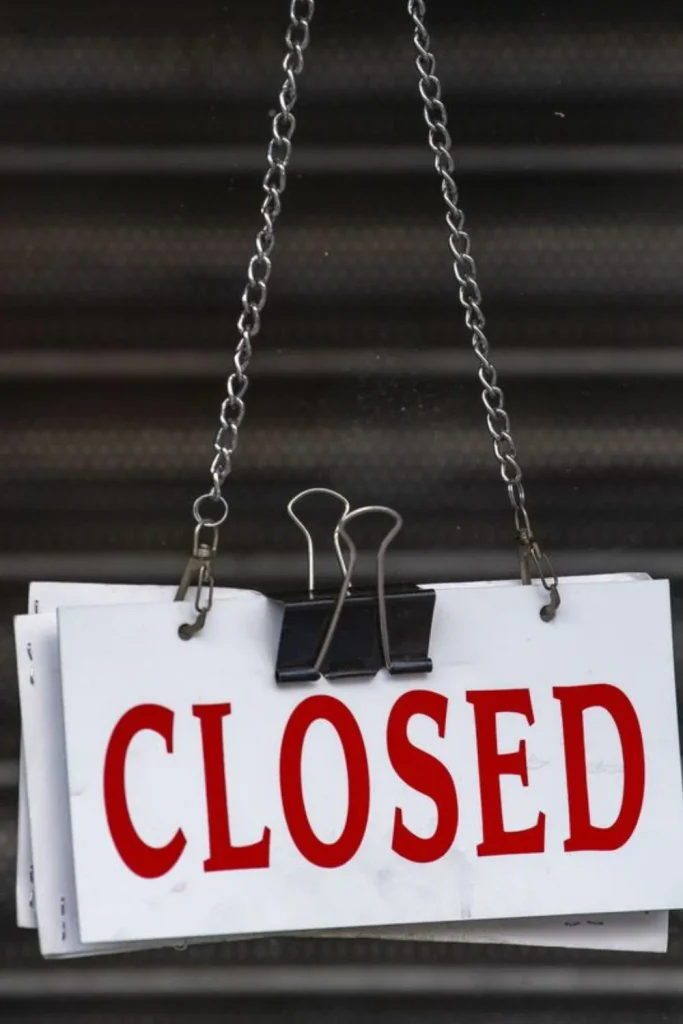Closed" sign hanging on a shuttered storefront door