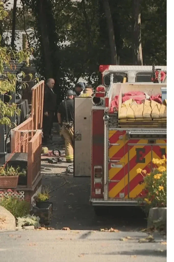 Firefighters and officials beside a fire engine in a Johnston yard during the open sewer dog rescue

