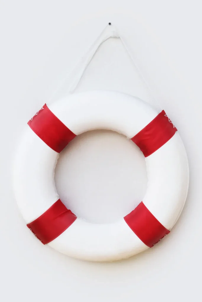 White and red life ring buoy hanging against a plain wall